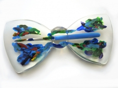 Kleiner Pinsel und Farben blau und grün, eingebettet in transparentes Kunstharz